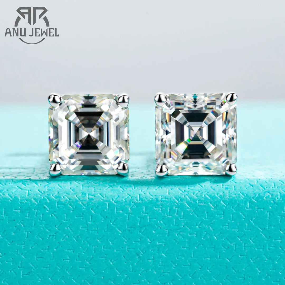 Pair of square-cut diamond earrings on a turquoise surface with 'ANU JEWEL' branding.