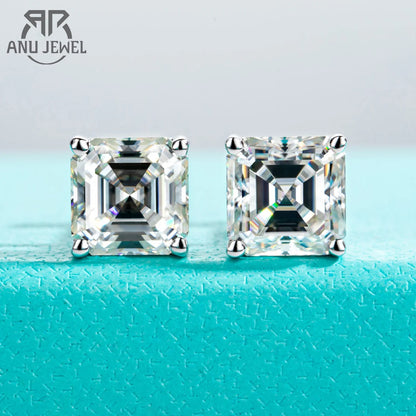 Pair of square-cut diamond earrings on a turquoise surface with 'ANU JEWEL' branding.