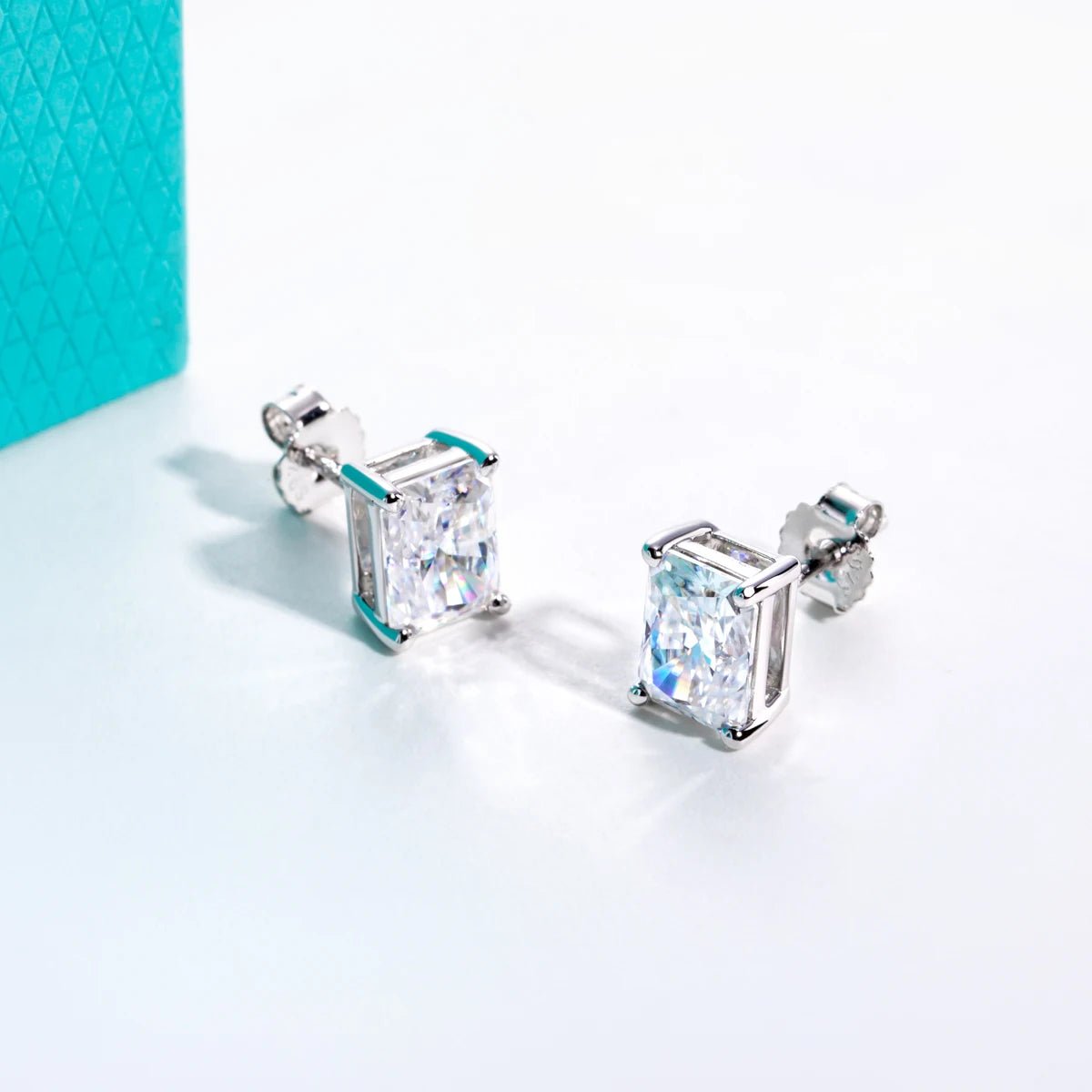 Pair of silver stud earrings with clear gemstones on a light blue background