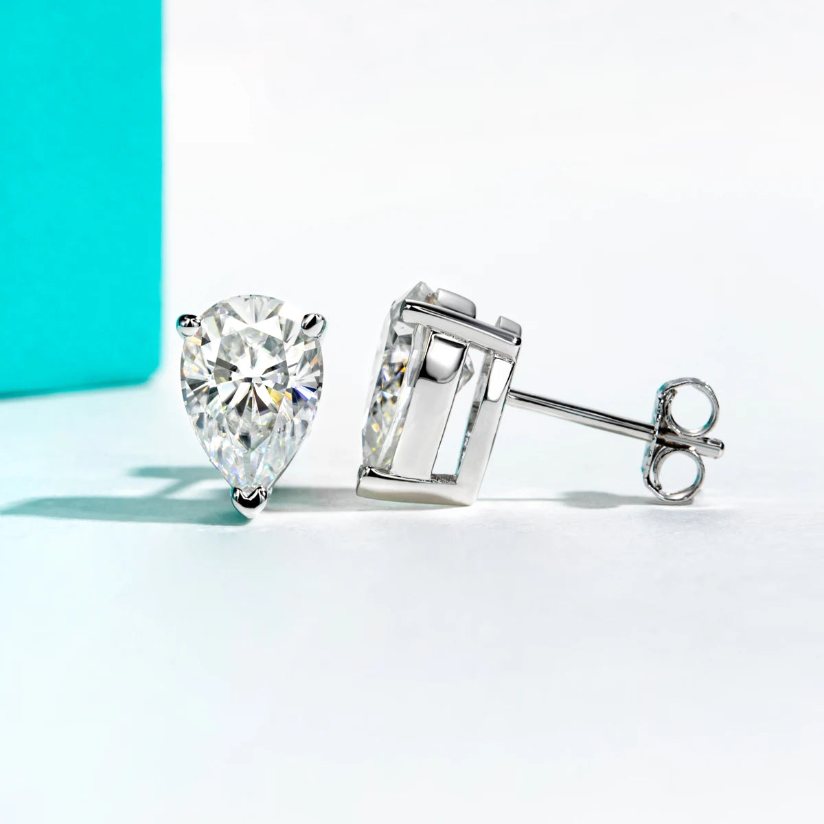Two diamond earrings on a light blue and white background
