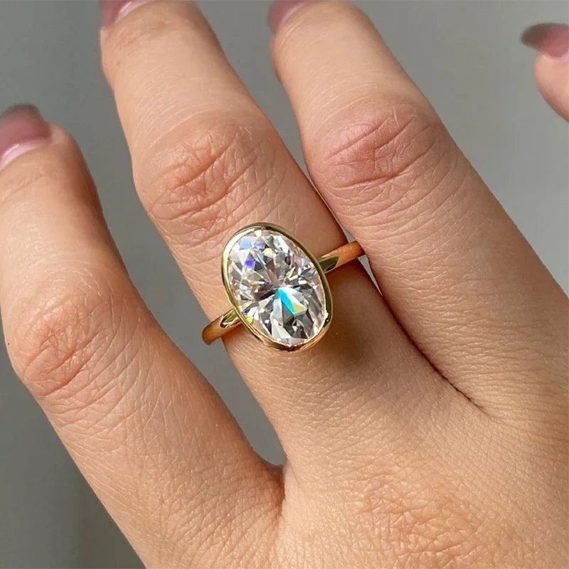 Gold ring with a large diamond on a hand against a neutral background