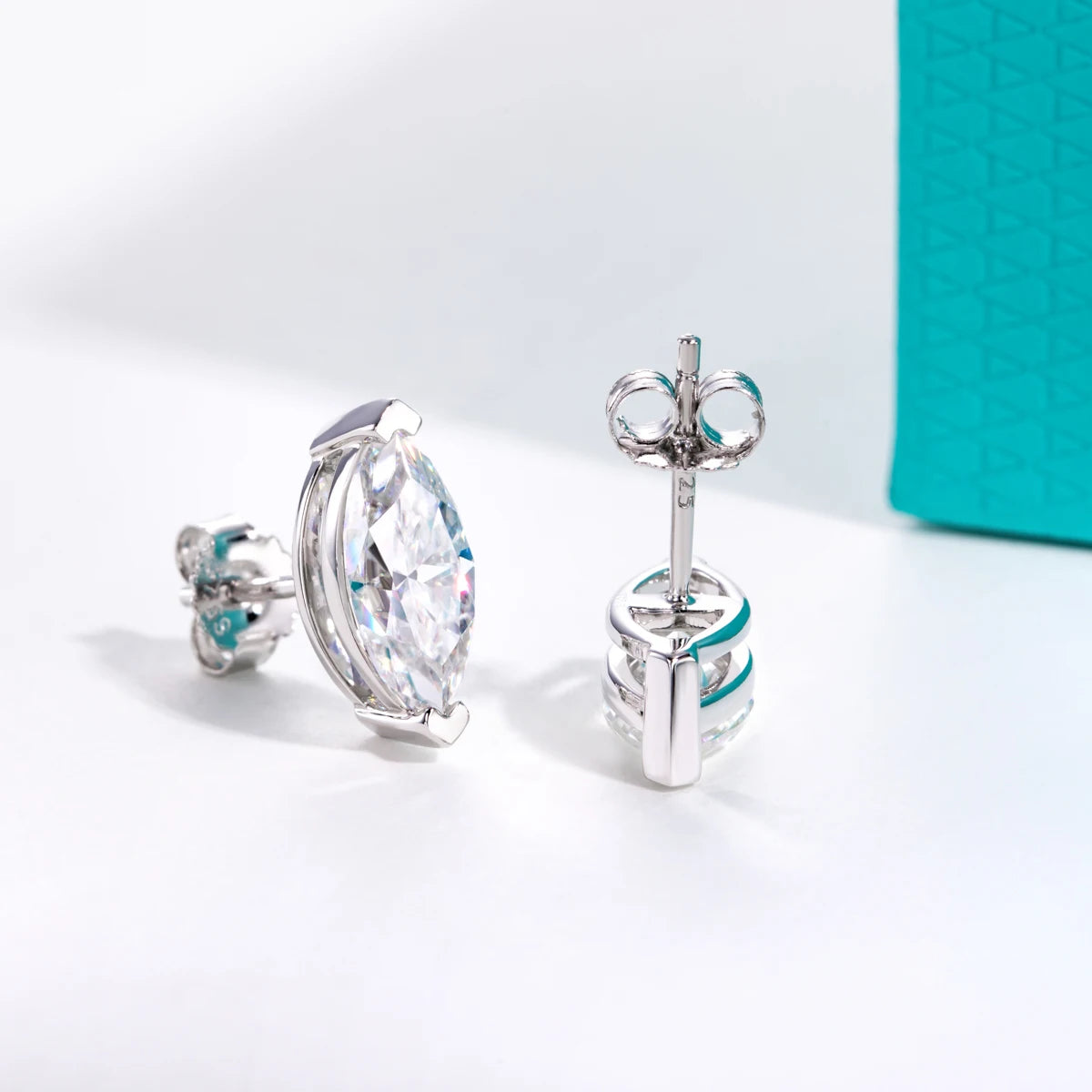 Silver earrings with large clear gemstones on a light gray background