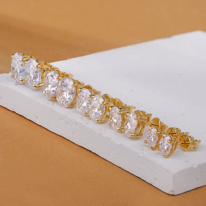 Gold bracelet with clear gemstones on a white stand against a beige background