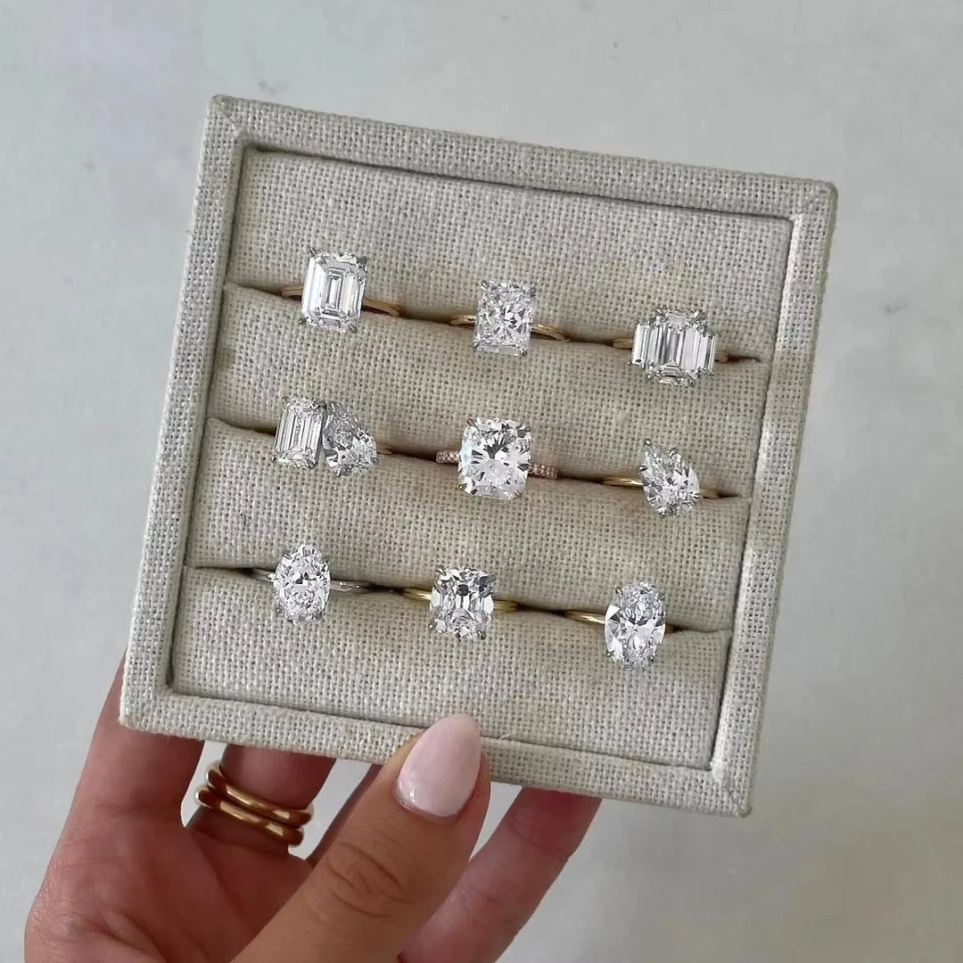 Set of diamond rings displayed on a textured card held by a hand.