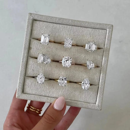 Set of diamond rings displayed on a textured card held by a hand.