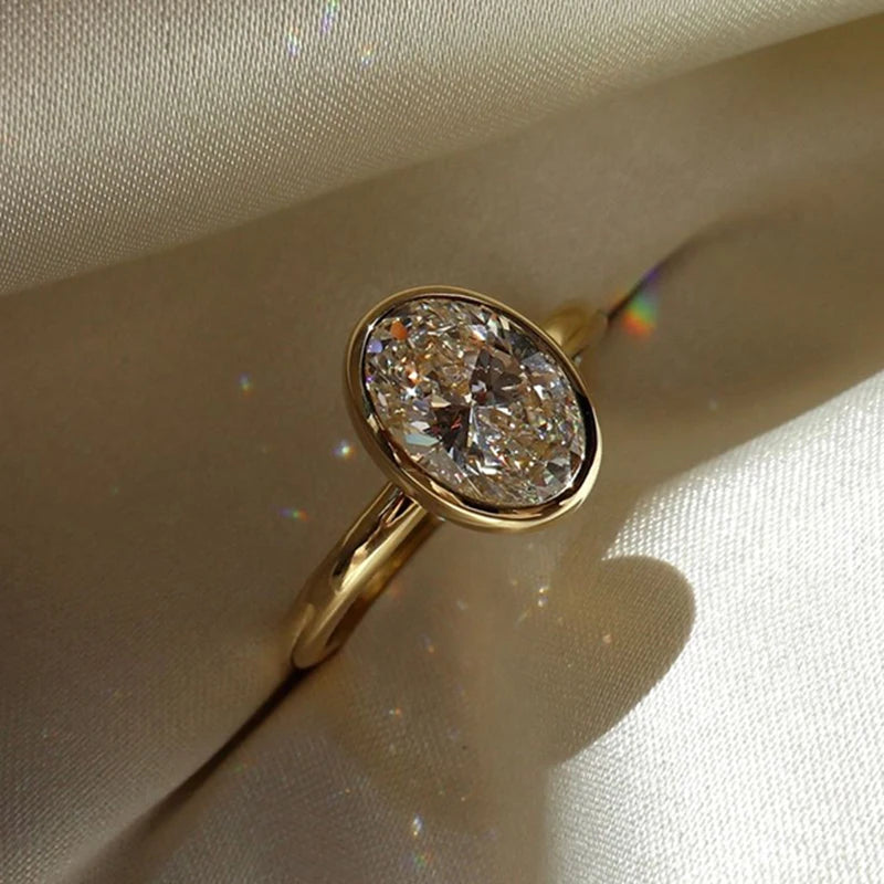 Gold ring with a large diamond on a beige fabric background