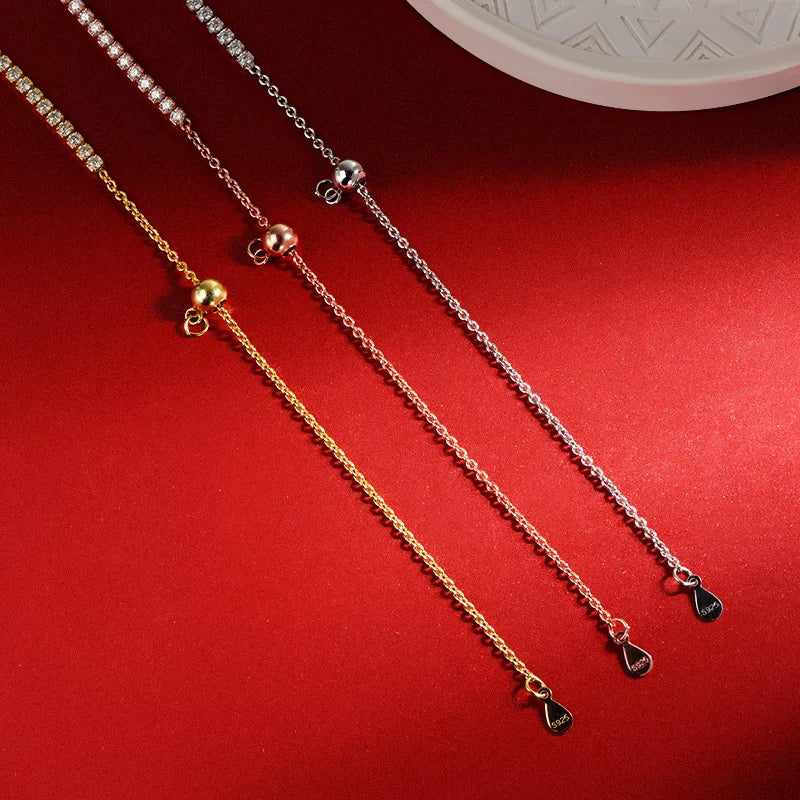 Two gold necklaces with heart-shaped pendants on a red surface