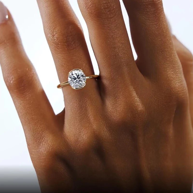 Gold ring with a diamond on a person's finger against a white background