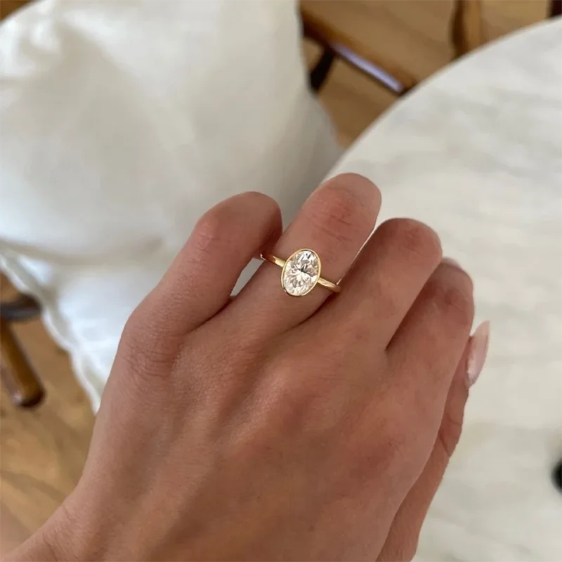 Gold ring with a diamond on a hand against a blurred indoor background