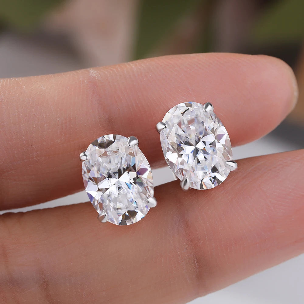 Diamond earrings held between two fingers against a blurred background
