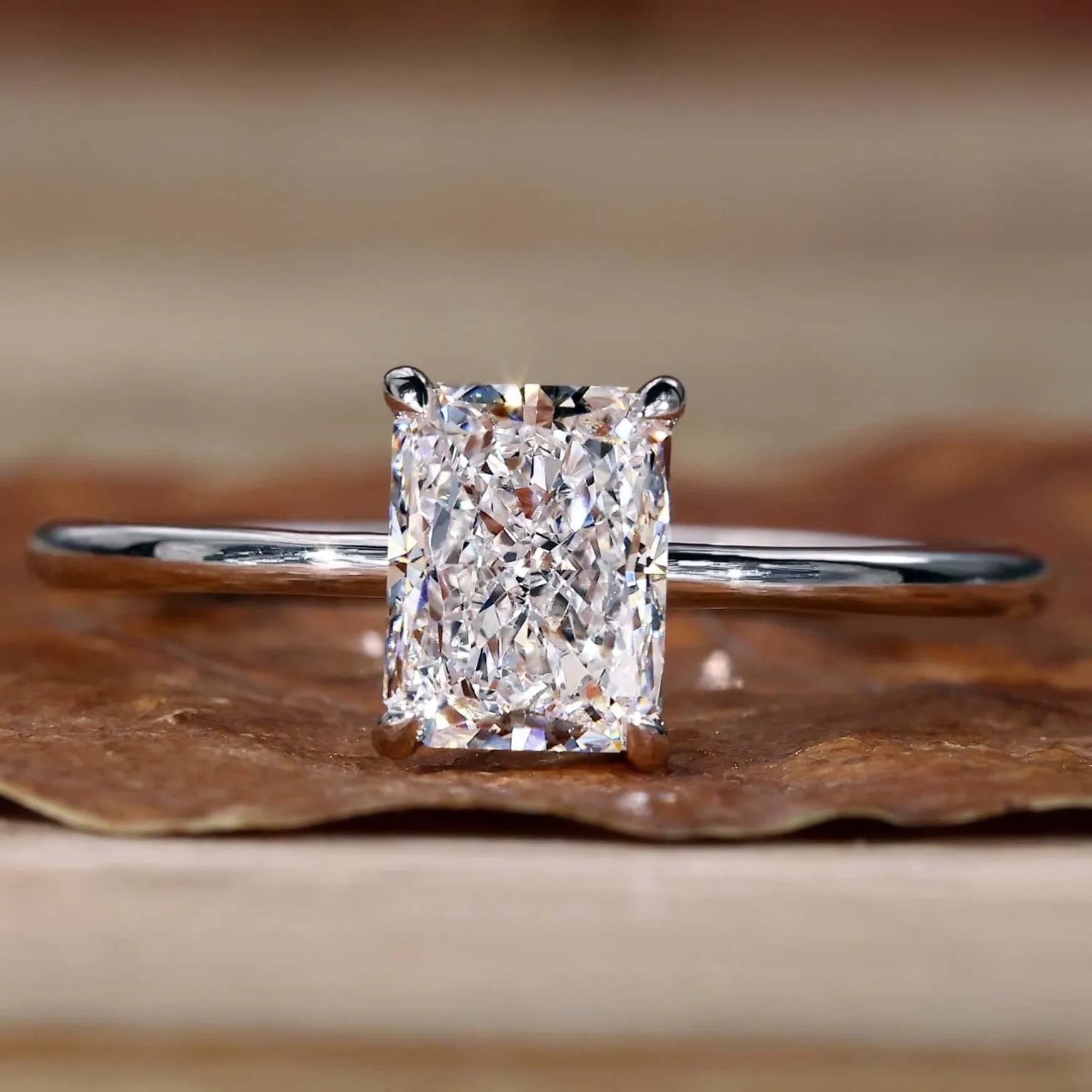 Diamond ring with a rectangular cut stone on a wooden surface