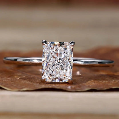 Diamond ring with a rectangular cut stone on a wooden surface