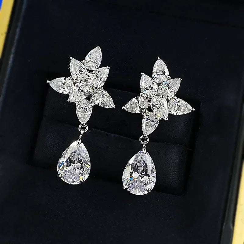 Pair of silver earrings with floral designs and teardrop shapes on a black background