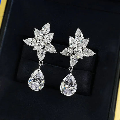 Pair of silver earrings with floral designs and teardrop shapes on a black background