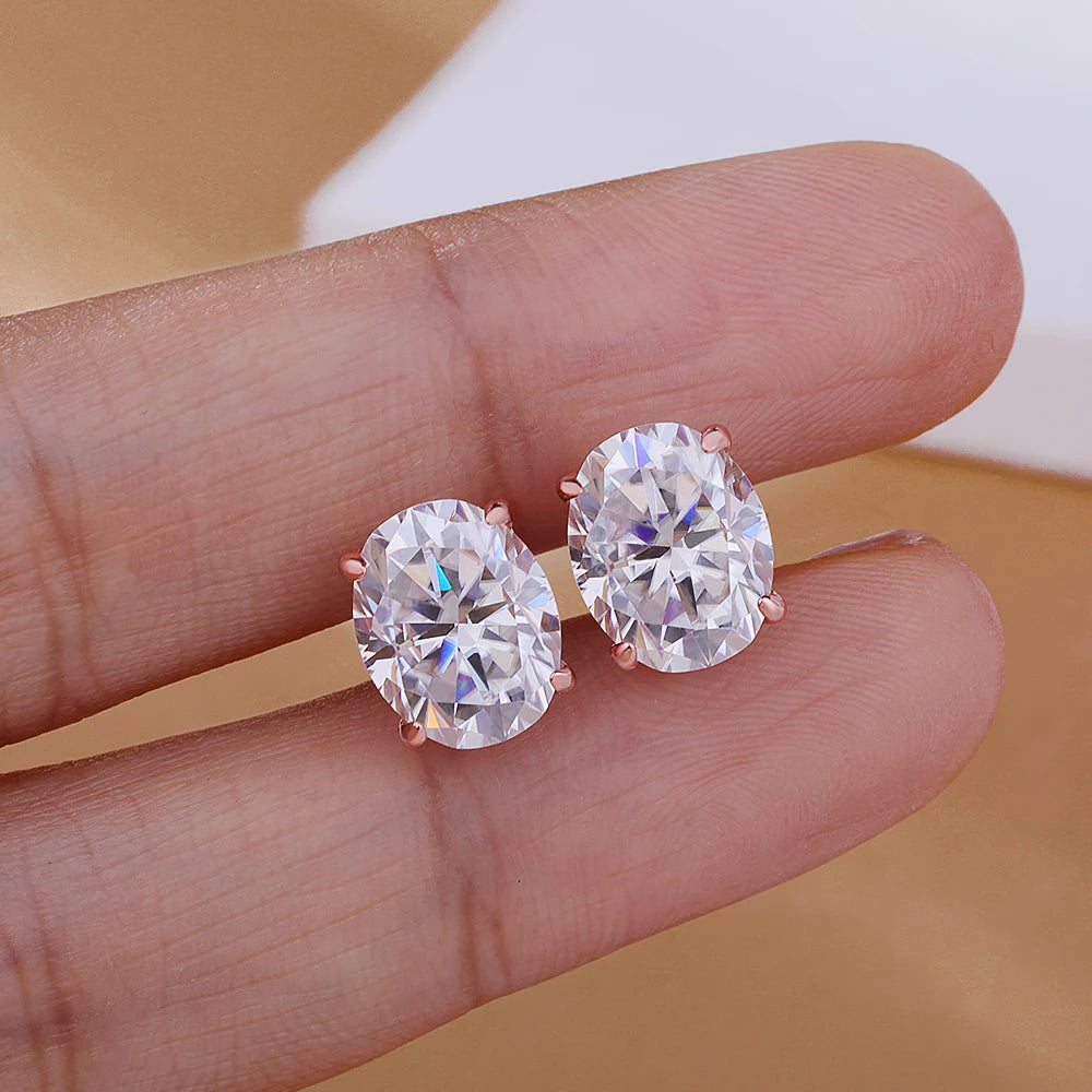 Diamond earrings held between fingers against a neutral background