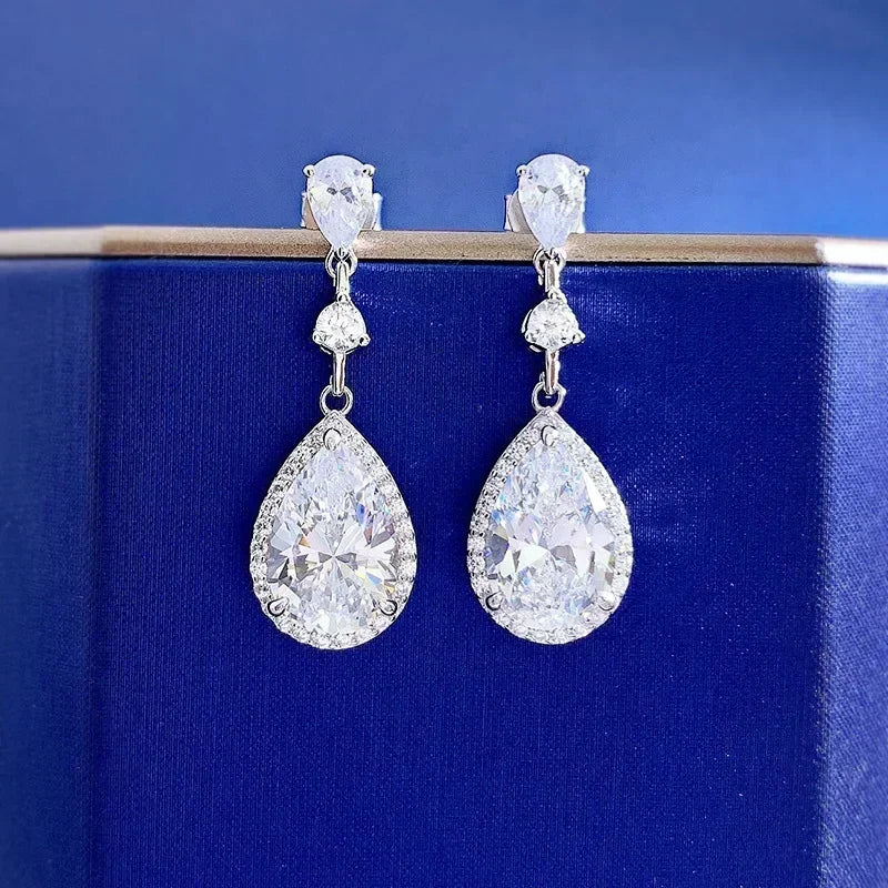 Teardrop-shaped earrings with clear gemstones on a blue background