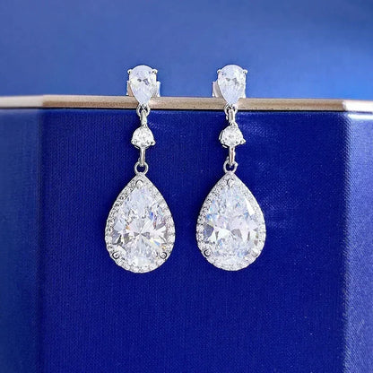 Teardrop-shaped earrings with clear gemstones on a blue background