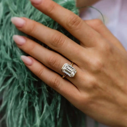 Hand wearing a diamond ring with a green textured background