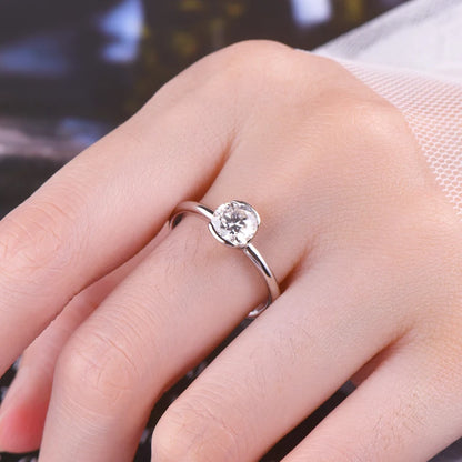 Silver ring with a diamond on a person's finger against a blurred background