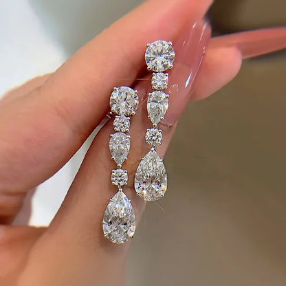 Diamond earrings held by a hand with a blurred background