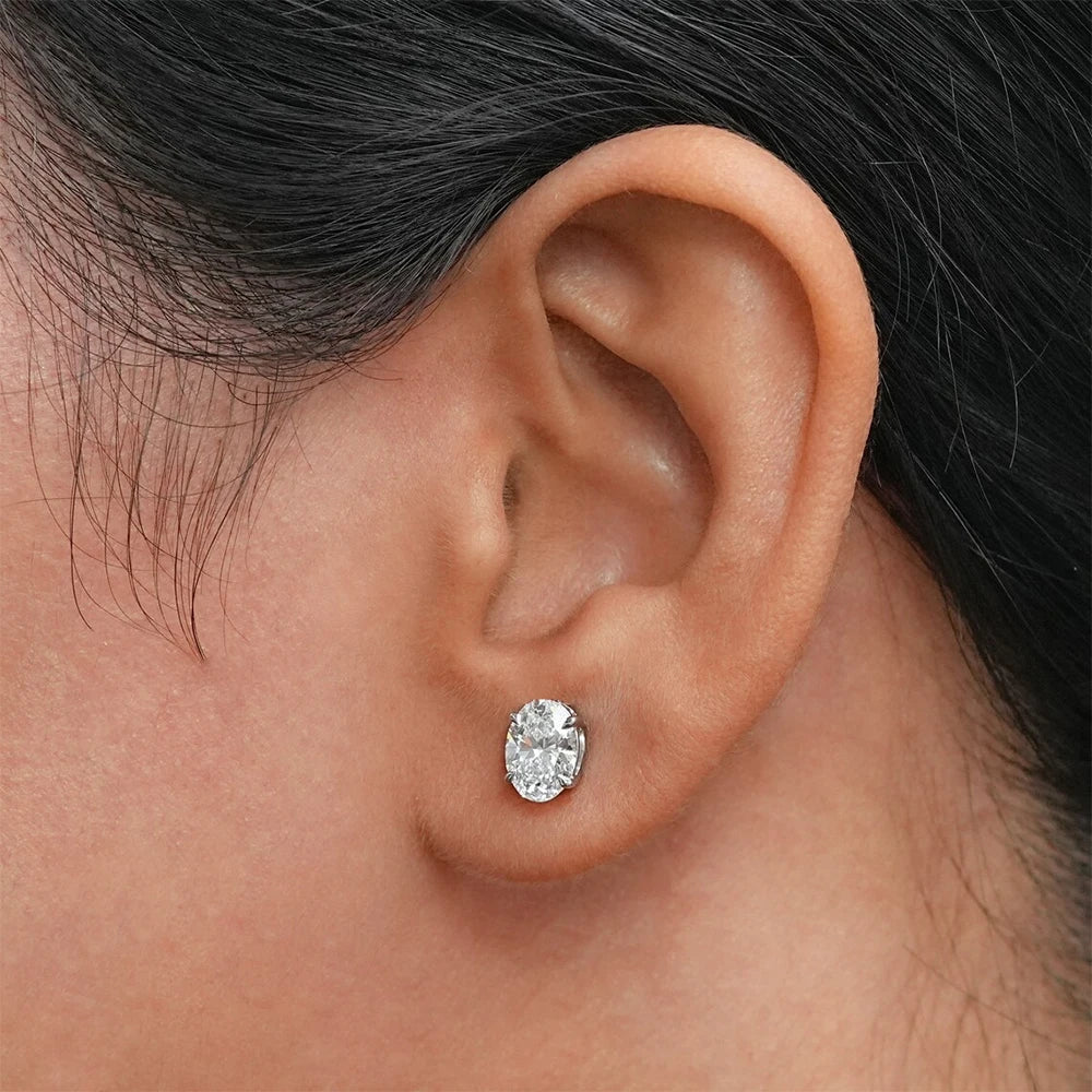 Close-up of an ear wearing a diamond stud earring with hair partially covering the frame.