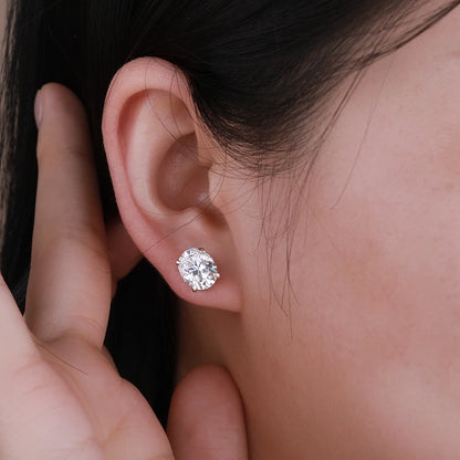 Close-up of an ear wearing a diamond earring with a hand adjusting it.