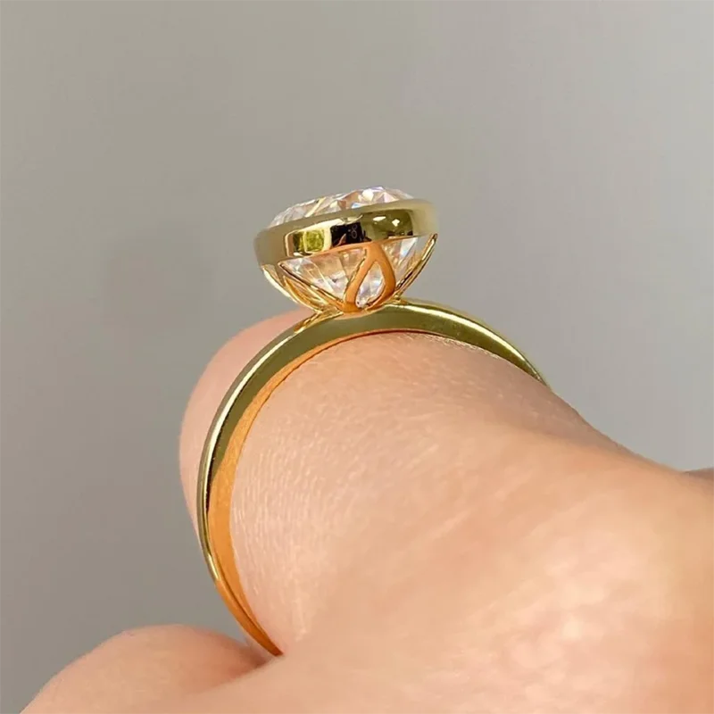 Gold ring with a diamond on a finger against a gray background