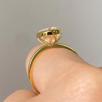 Gold ring with a diamond on a finger against a gray background
