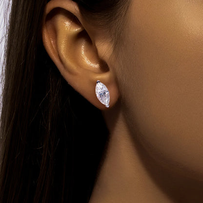 Close-up of an ear wearing a diamond earring with a neutral background