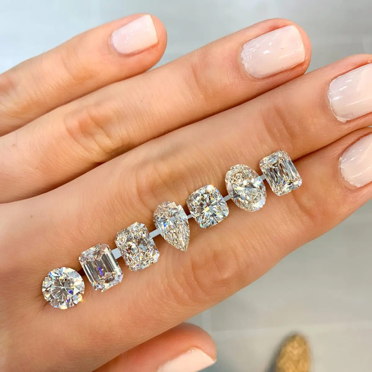 Diamond earrings on a hand with a neutral background