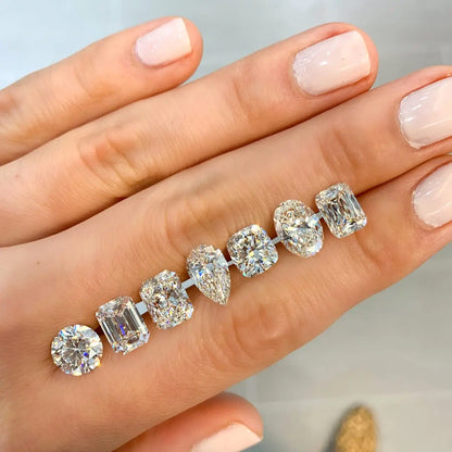 Diamond earrings on a hand with a neutral background