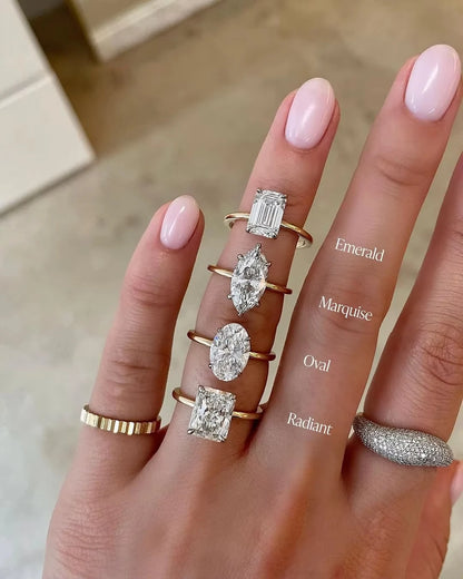 Hand wearing various diamond rings with different shapes on a neutral background