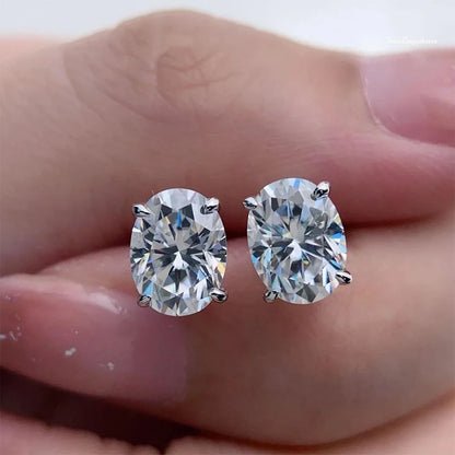 Pair of diamond stud earrings held between fingers