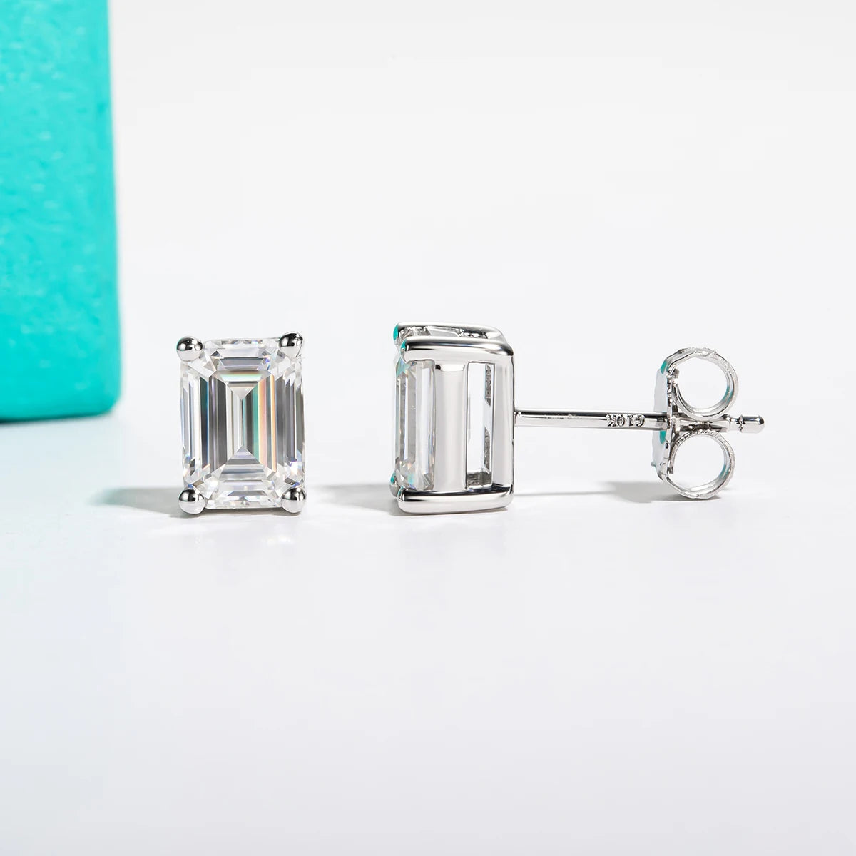 Pair of diamond stud earrings on a white background with a turquoise box.