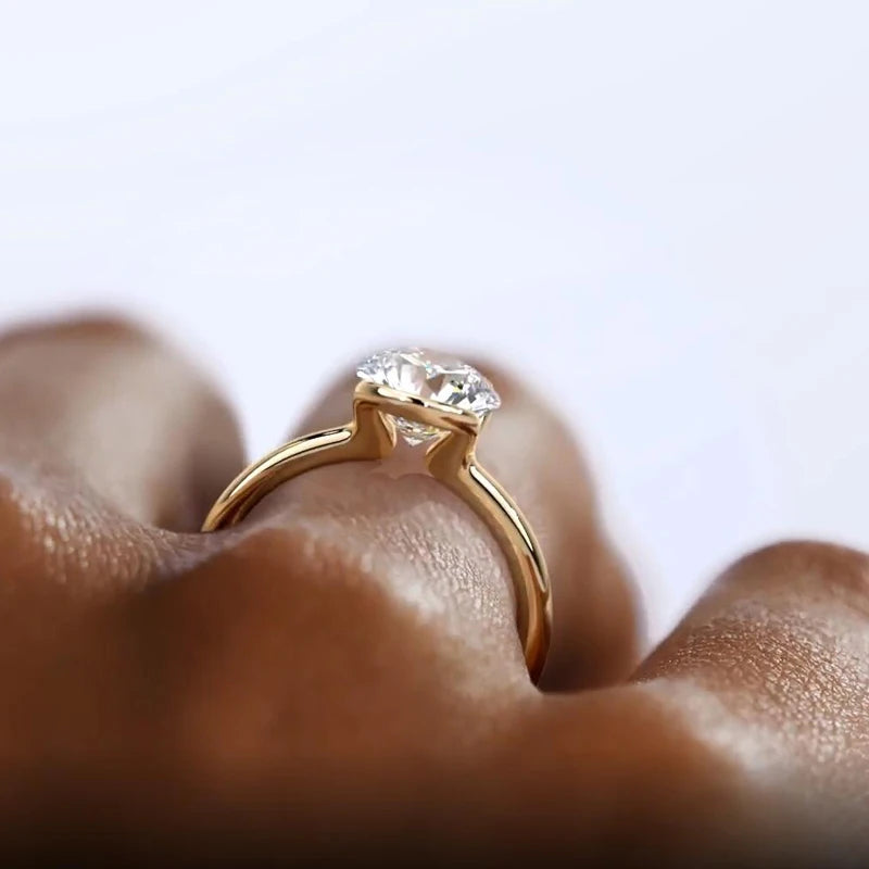 Gold ring with a diamond on a finger against a light background