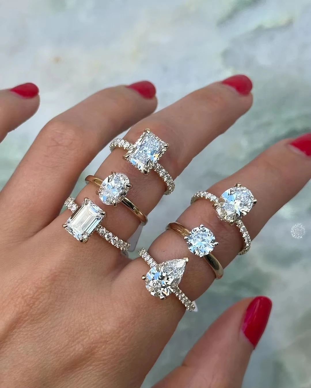 Hand wearing multiple diamond rings with a blurred background