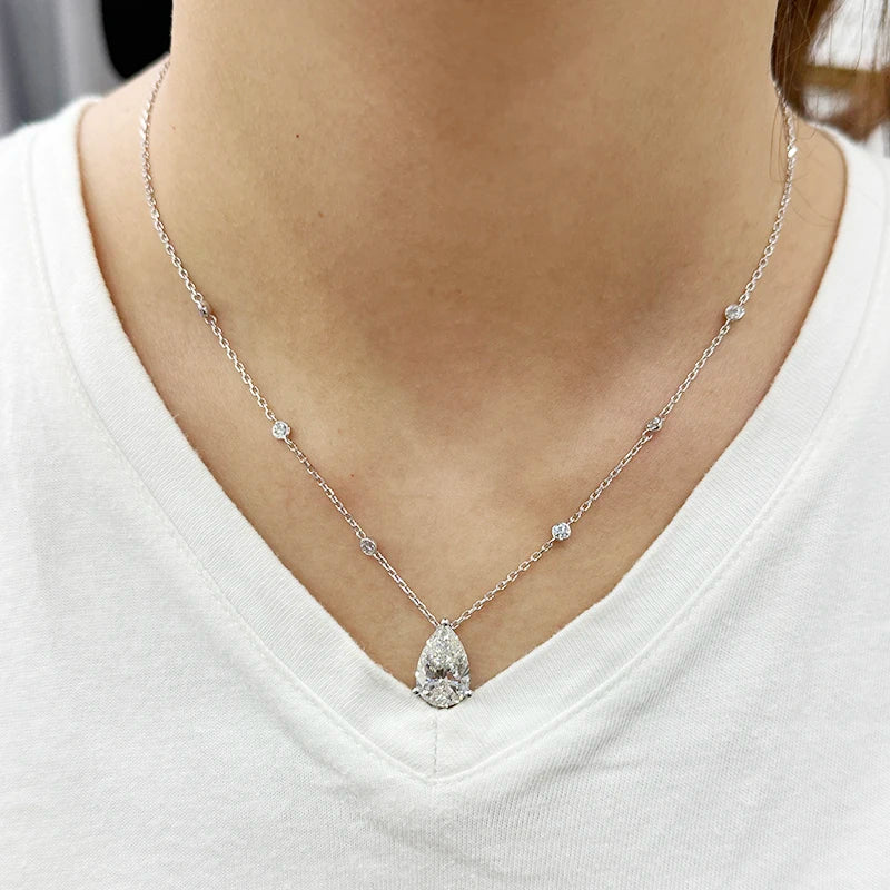 Silver necklace with a teardrop pendant worn by a person on a white shirt
