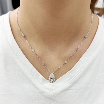Silver necklace with a teardrop pendant worn by a person on a white shirt