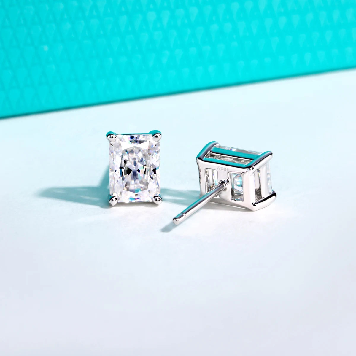Silver stud earrings with clear gemstones on a light blue background