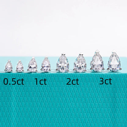 Teardrop-shaped diamonds of different carat weights on a teal background