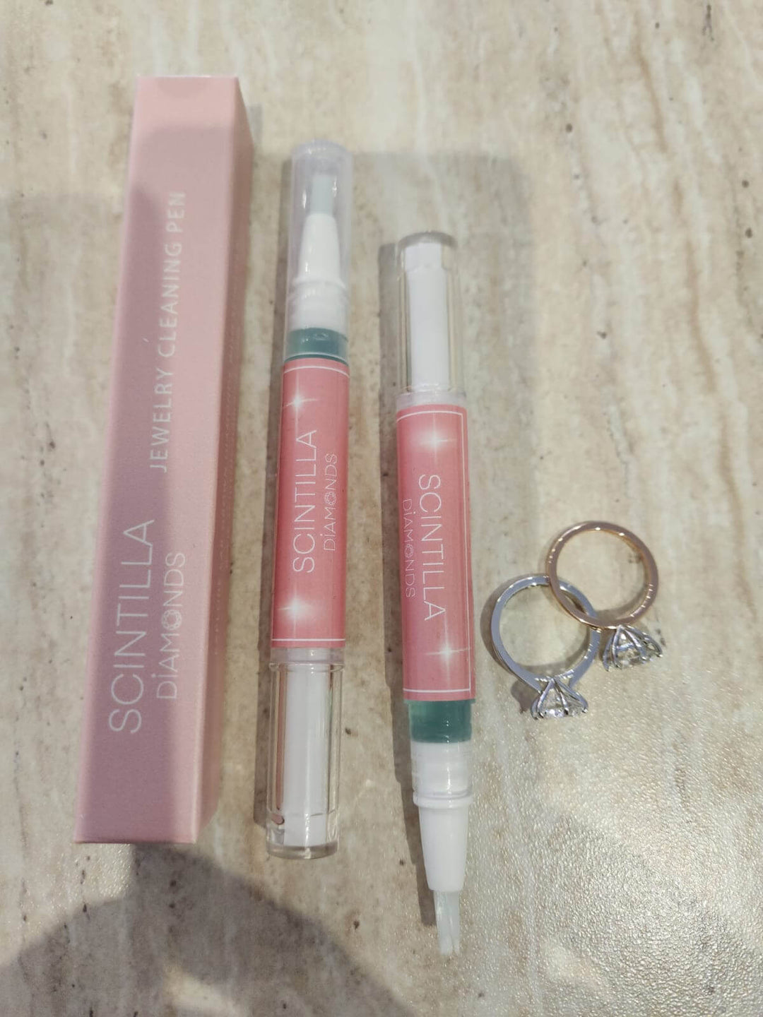 Scintilla jewelry cleaning pen with packaging and a ring on a wooden surface