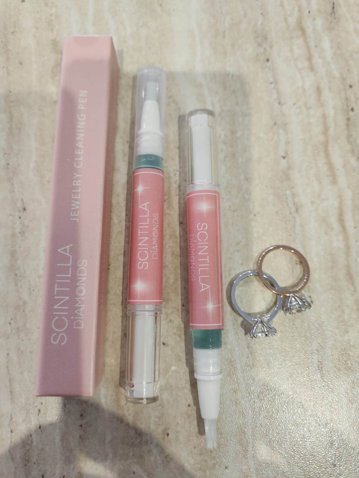 Scintilla jewelry cleaning pen with packaging and a ring on a wooden surface