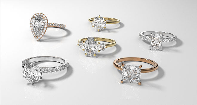 Collection of diamond rings in various designs and metals on a light gray background